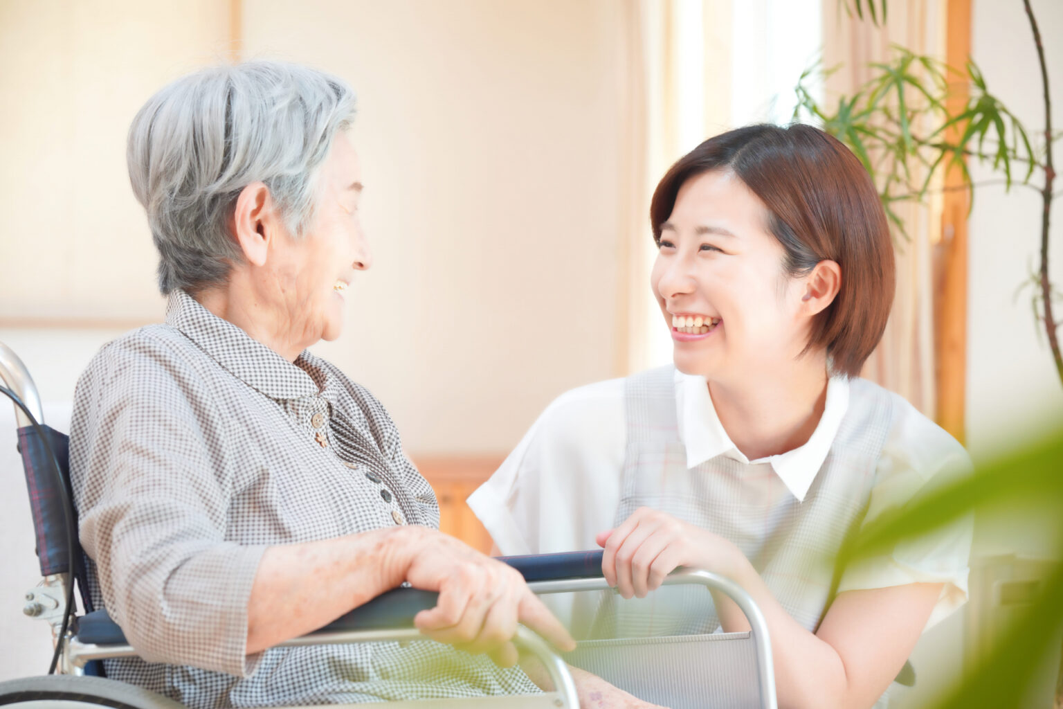 介護職員と高齢者の温かな交流風景。笑顔で向き合う両者の信頼関係が伝わります。